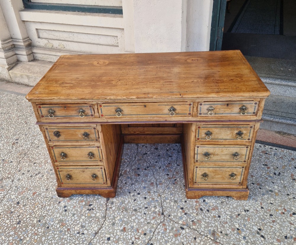 An Arts and Crafts pitch pine pedestal desk featuring nine drawers with hand-painted line borders and metal ring handles. View III