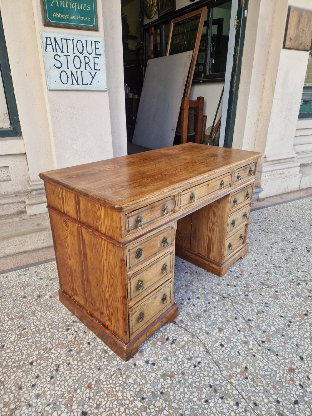 An Arts and Crafts pitch pine pedestal desk featuring nine drawers with hand-painted line borders and metal ring handles. View IV