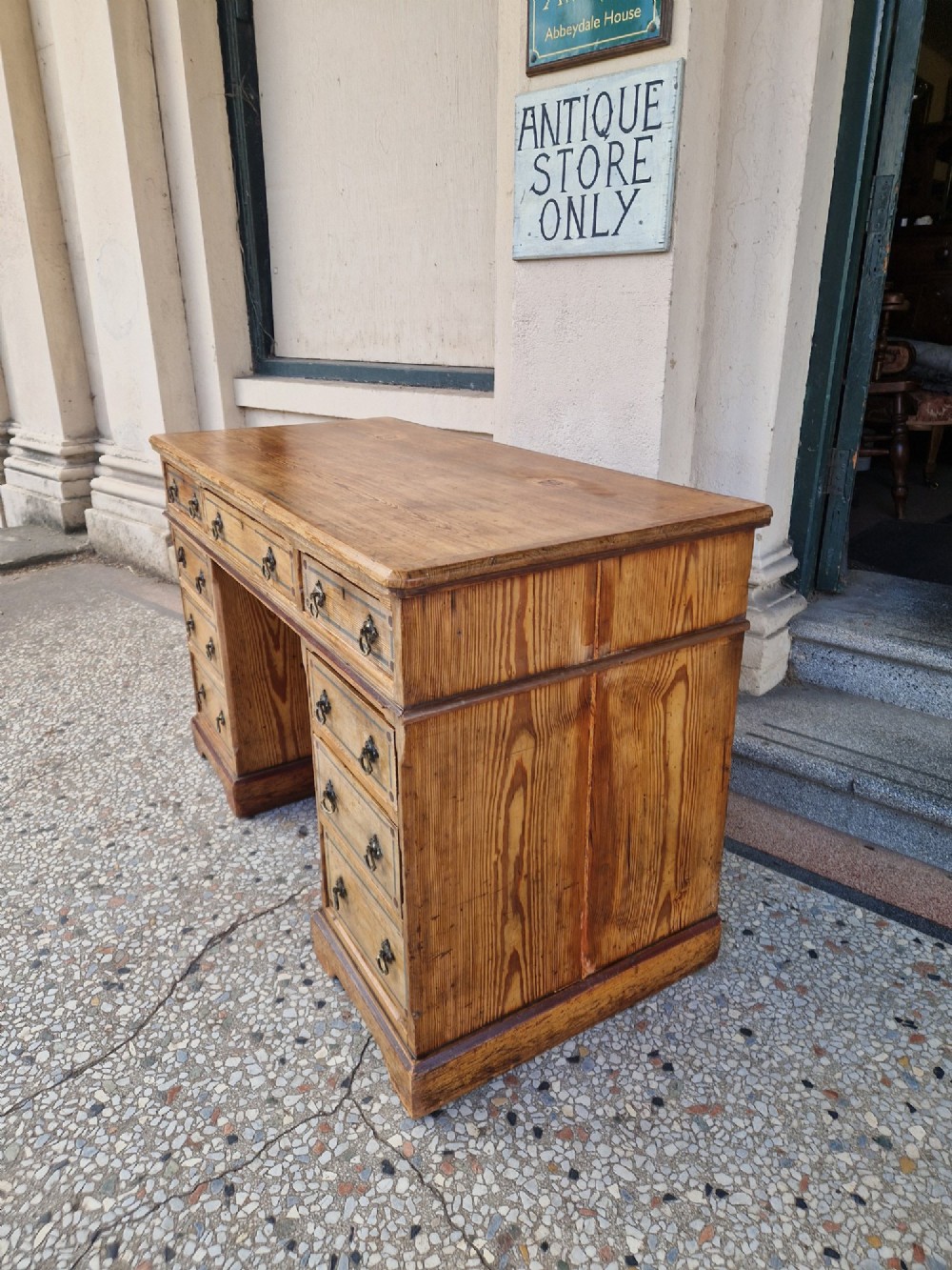 An Arts and Crafts pitch pine pedestal desk featuring nine drawers with hand-painted line borders and metal ring handles. View V