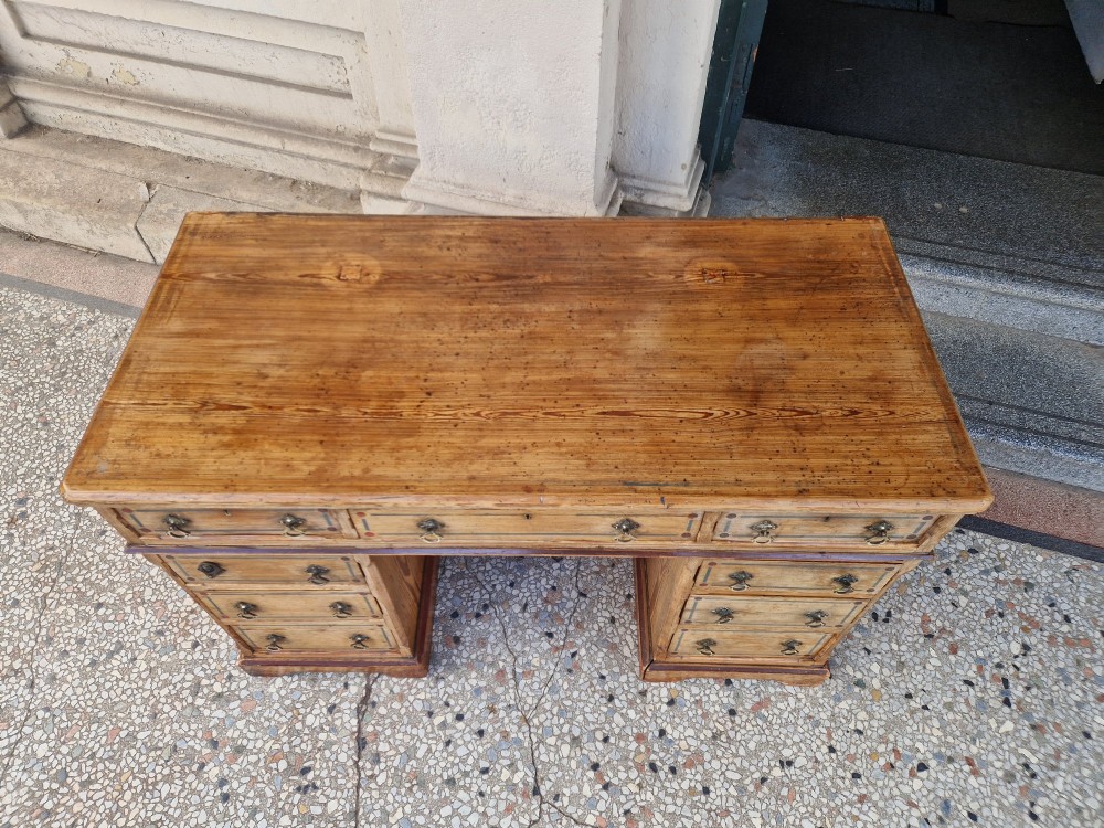 An Arts and Crafts pitch pine pedestal desk featuring nine drawers with hand-painted line borders and metal ring handles. View VI
