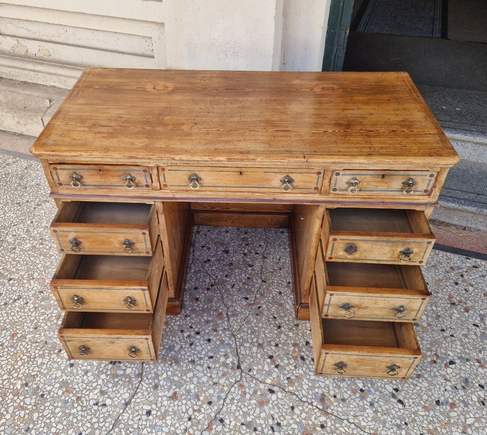 An Arts and Crafts pitch pine pedestal desk featuring nine drawers with hand-painted line borders and metal ring handles. View VIII
