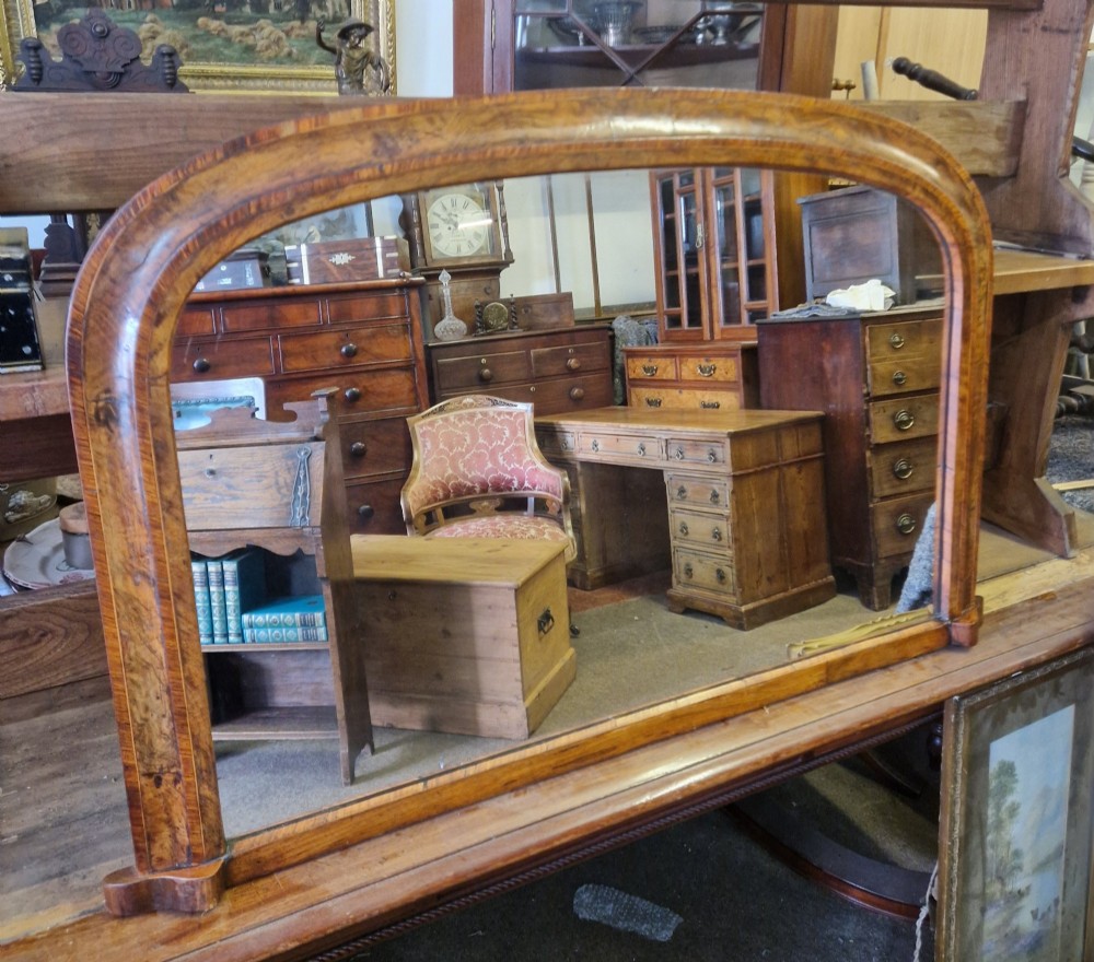 A Victorian burr walnut overmantel mirror featuring a curved arched top frame resting on flat moulding blocks.