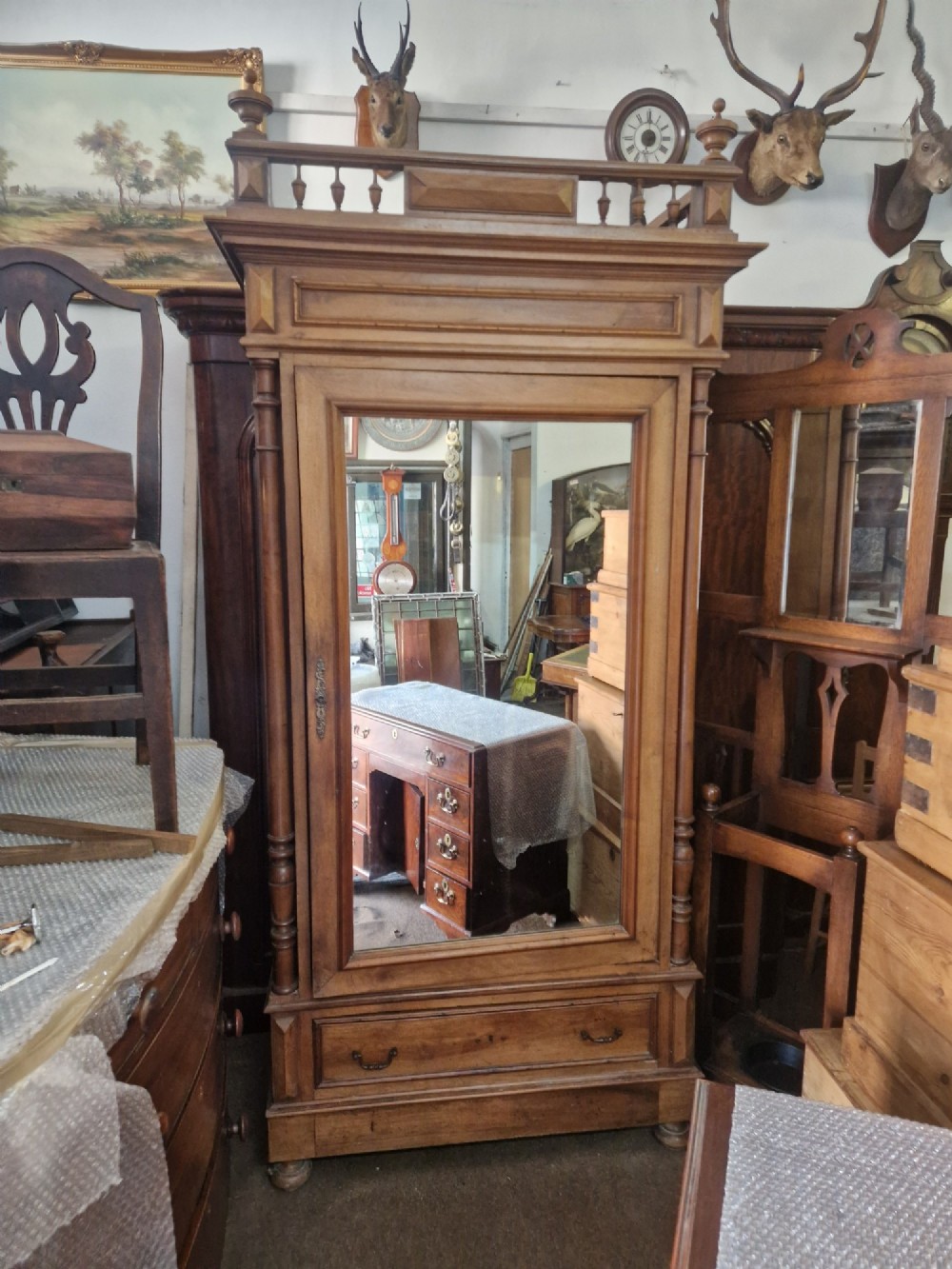 An antique burr walnut single-door armoire with a central bevelled mirror, flanking turned columns, and a lower drawer. View IV