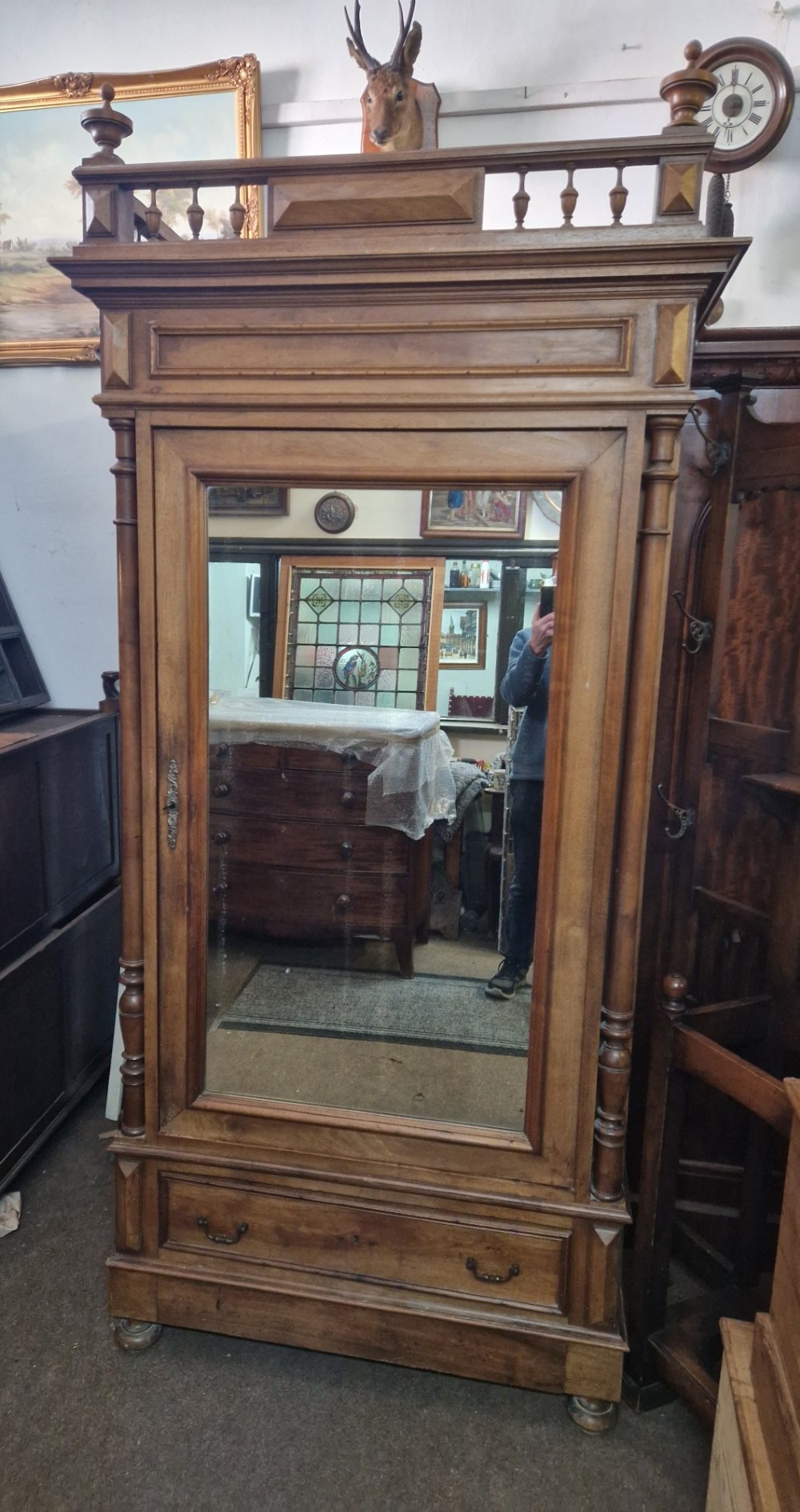 An antique burr walnut single-door armoire with a central bevelled mirror, flanking turned columns, and a lower drawer. View V