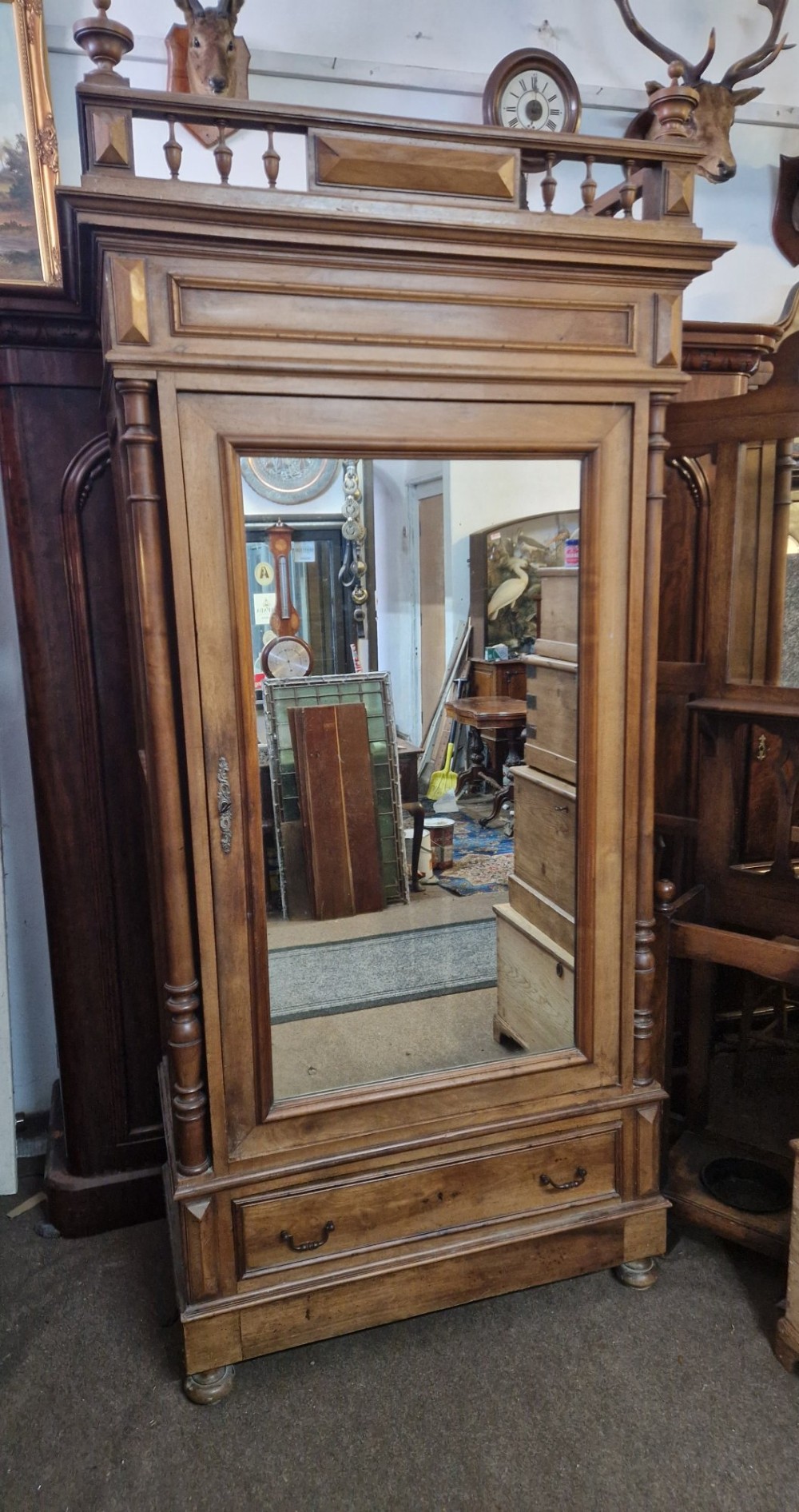 An antique burr walnut single-door armoire with a central bevelled mirror, flanking turned columns, and a lower drawer. View VI