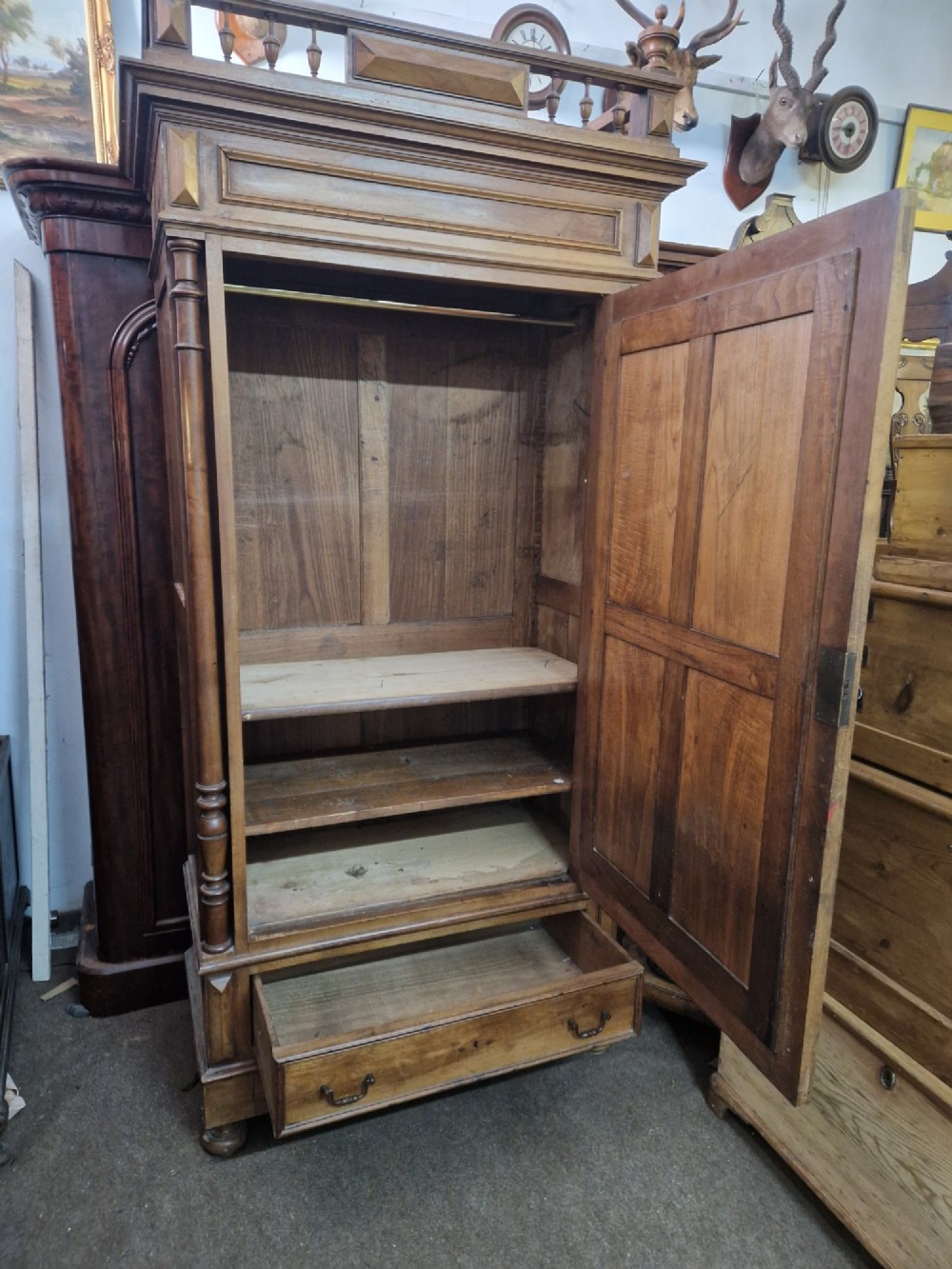 An antique burr walnut single-door armoire with a central bevelled mirror, flanking turned columns, and a lower drawer. View X