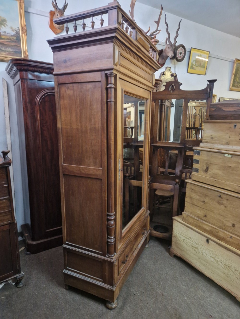 An antique burr walnut single-door armoire with a central bevelled mirror, flanking turned columns, and a lower drawer. View XI