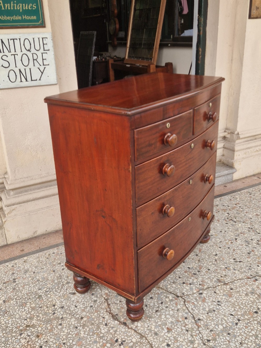 A Victorian mahogany bow fronted chest of drawers featuring two short over three long drawers with turned wooden handles and brass escutcheons on turned feet. View II
