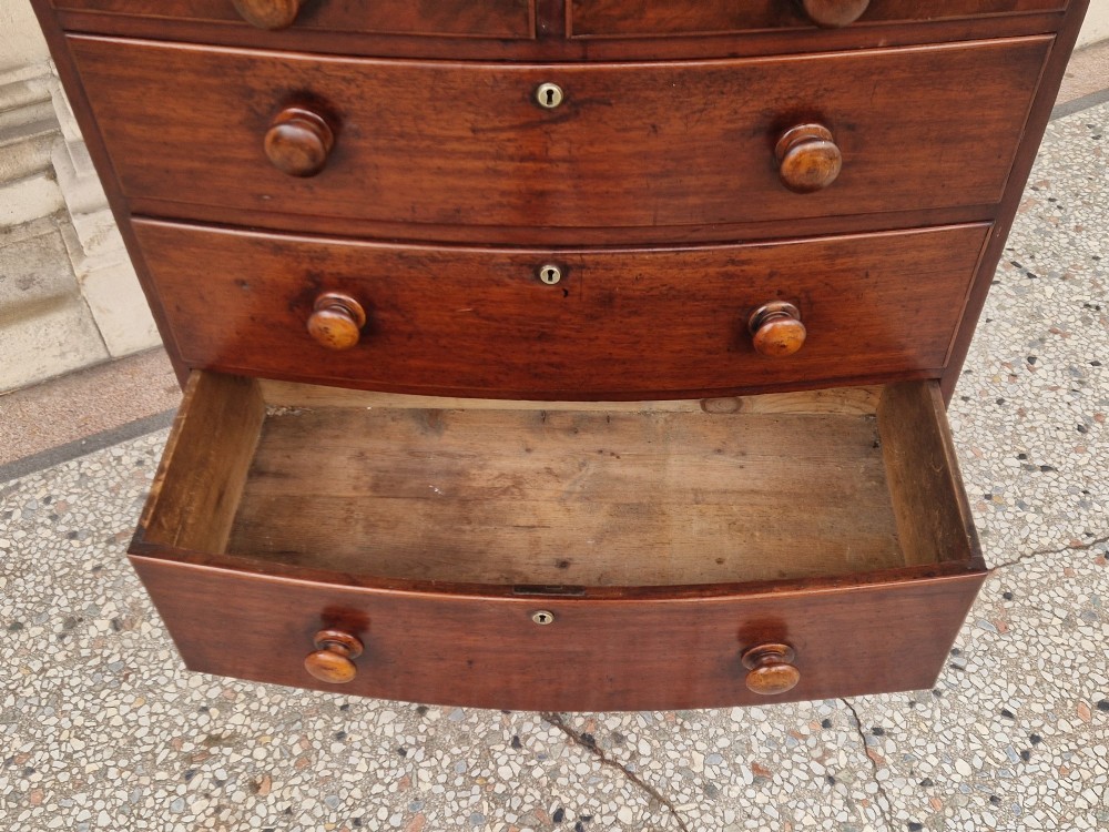 A Victorian mahogany bow fronted chest of drawers featuring two short over three long drawers with turned wooden handles and brass escutcheons on turned feet. View IV