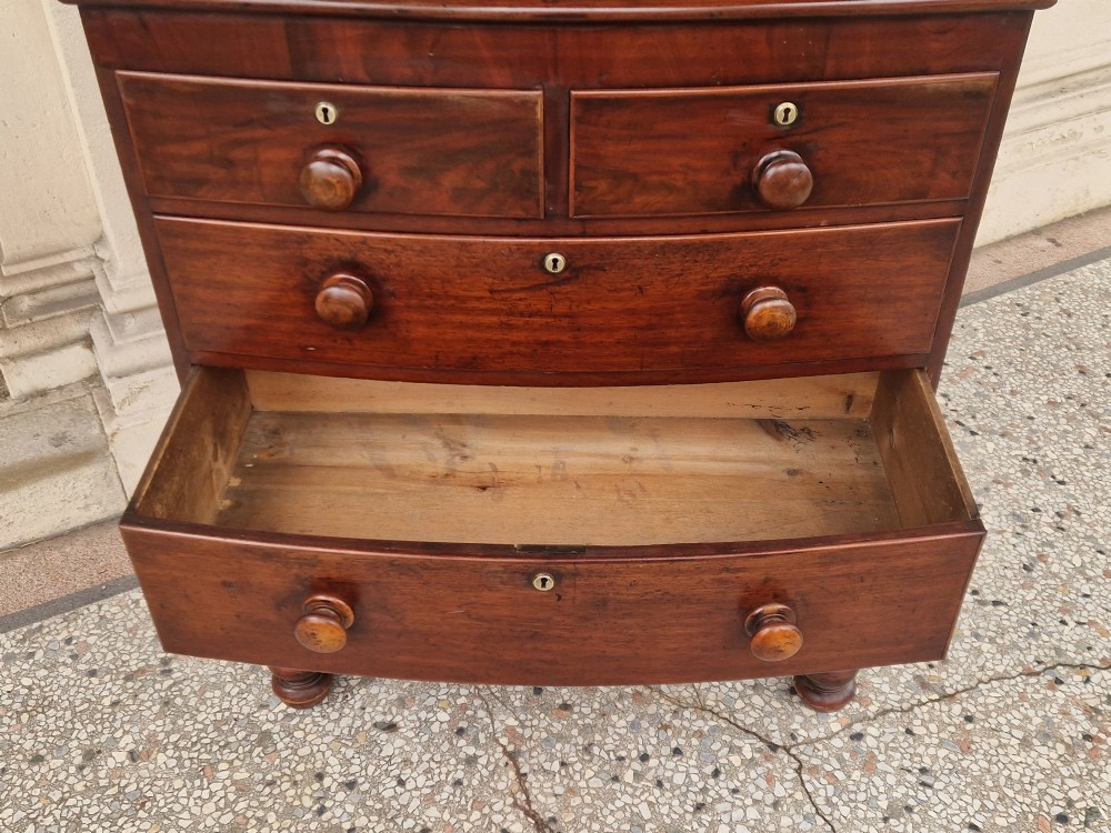 A Victorian mahogany bow fronted chest of drawers featuring two short over three long drawers with turned wooden handles and brass escutcheons on turned feet. View VII