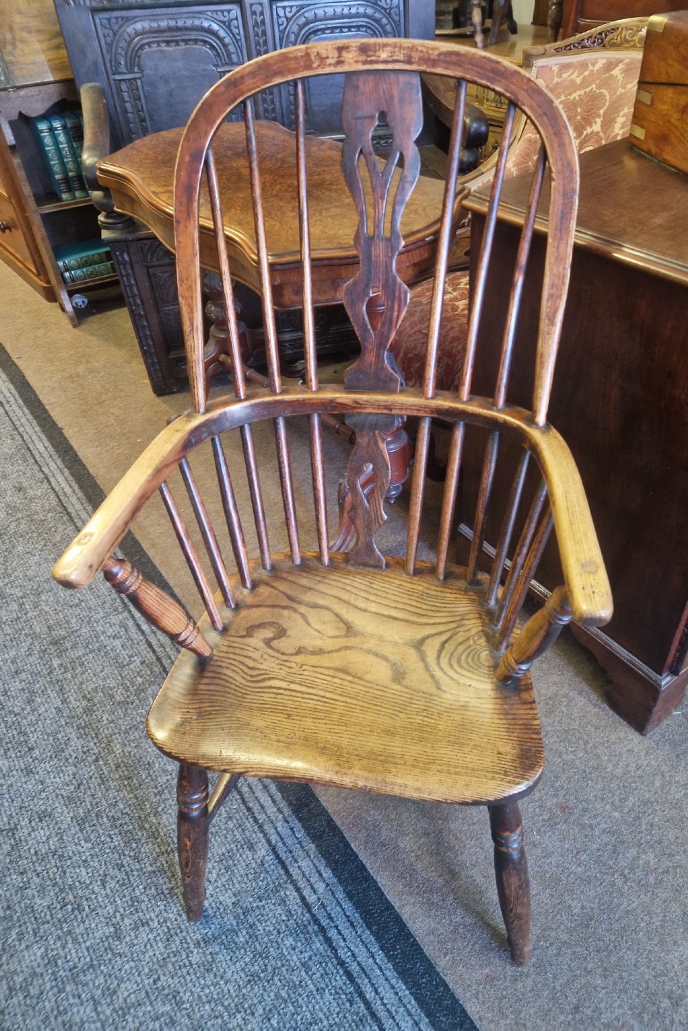An antique ash and elm Windsor armchair with a hoop back, central pierced splat, turned spindles, shaped wooden seat, and turned legs joined by an H-stretcher. View II
