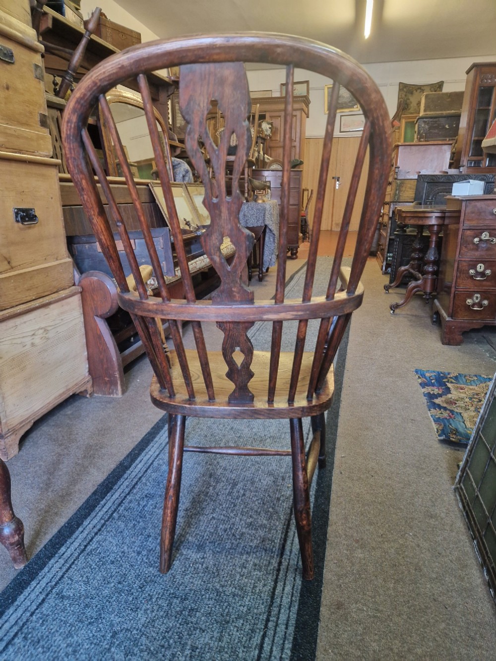 An antique ash and elm Windsor armchair with a hoop back, central pierced splat, turned spindles, shaped wooden seat, and turned legs joined by an H-stretcher. View IV