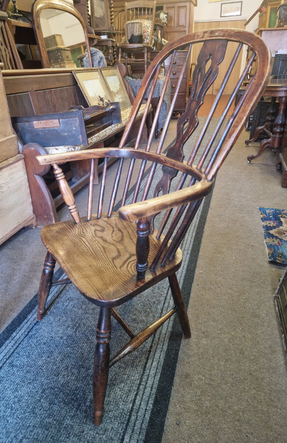 An antique ash and elm Windsor armchair with a hoop back, central pierced splat, turned spindles, shaped wooden seat, and turned legs joined by an H-stretcher. View V