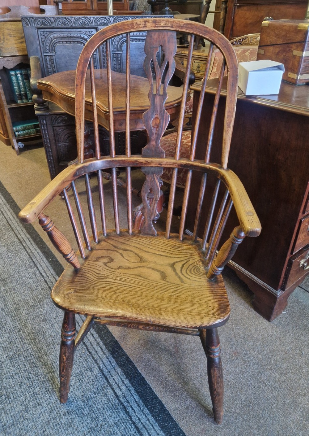 An antique ash and elm Windsor armchair with a hoop back, central pierced splat, turned spindles, shaped wooden seat, and turned legs joined by an H-stretcher. View VI