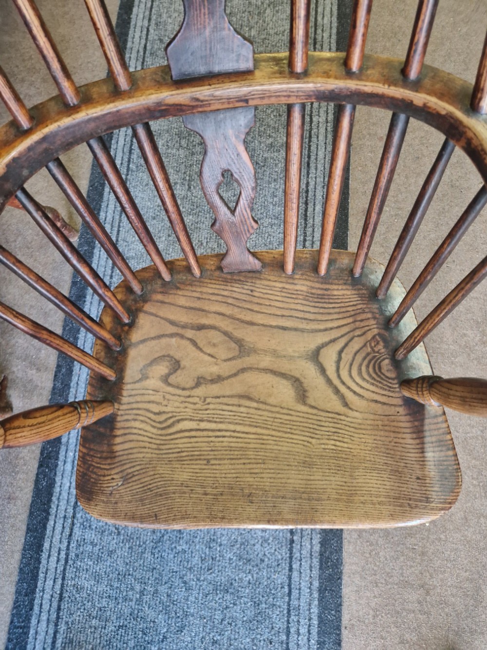 An antique ash and elm Windsor armchair with a hoop back, central pierced splat, turned spindles, shaped wooden seat, and turned legs joined by an H-stretcher. View VII