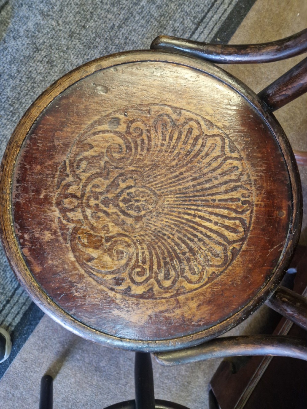 A pair of dark brown bentwood bistro chairs featuring spindle backrests and round wooden seats with embossed decorative shell motifs. View VI