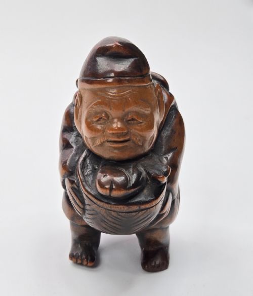 fig 3. A carved dark wood Japanese figurine depicting Ebisu holding a basket containing a sea bream fish.