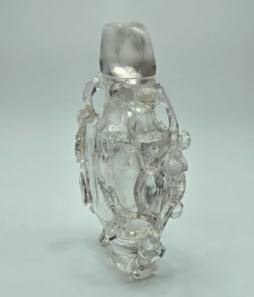 fig 5. A 19th-century Chinese carved clear rock crystal snuff bottle featuring openwork prunus branches around the body and a smooth matching stopper.