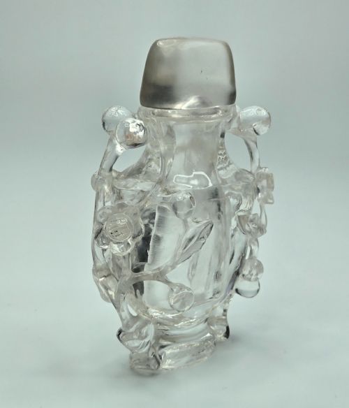 fig 6. A 19th-century Chinese carved clear rock crystal snuff bottle featuring openwork prunus branches around the body and a smooth matching stopper.