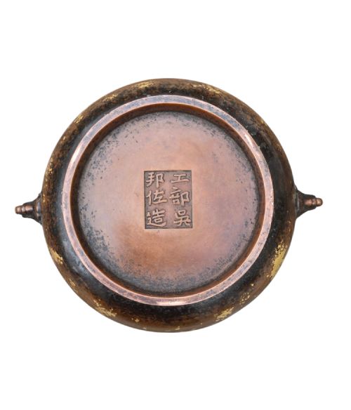 fig 5. A dark brown cast bronze incense burner featuring irregular gold splash decoration and detailed beast mask handles on either side.