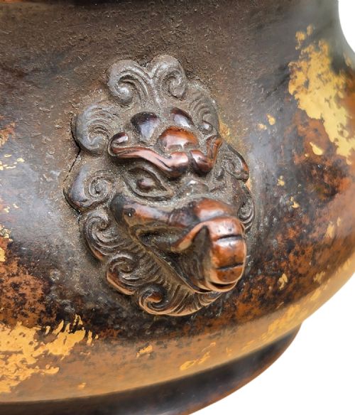 fig 7. A dark brown cast bronze incense burner featuring irregular gold splash decoration and detailed beast mask handles on either side.