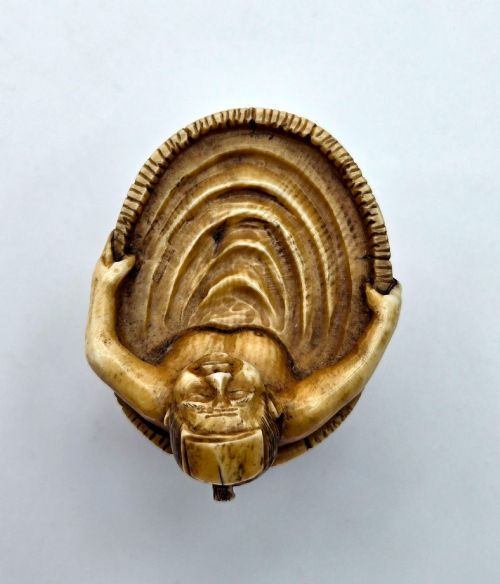 fig 3. A small carved stag antler netsuke depicting a man sitting inside a wooden bath tub with carved water ripples.