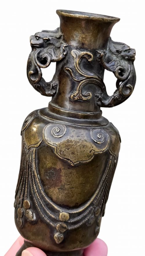 fig 3. A patinated cast bronze Chinese vase featuring stylised dragon-head handles and raised Yingluo beaded tassels.