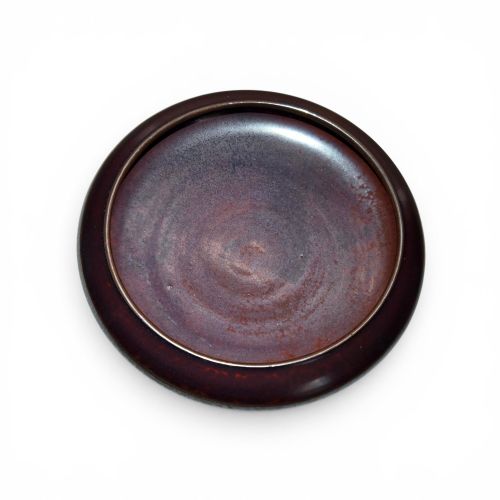fig 4. A low compressed circular ceramic brush washer featuring a dark reddish-brown iron rust glaze with subtle metallic speckling.