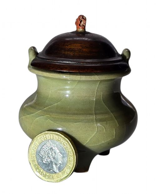 fig 4. A miniature pale celadon green tripod censer with a distinct crackle glaze, fitted with a dark wood cover and a carved red coral finial.