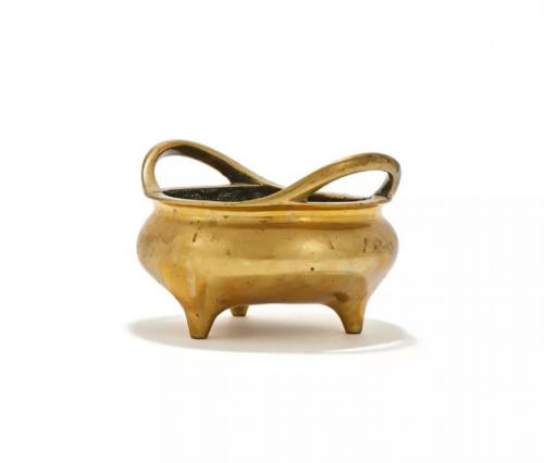fig 1. A heavy cast golden brass tripod censer featuring loop handles and three tapered feet.