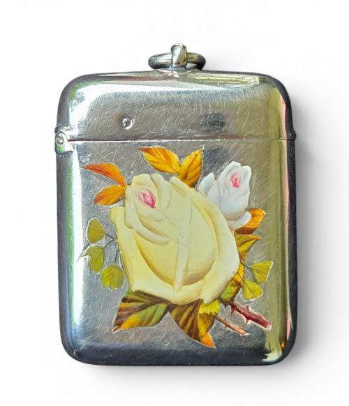 fig 2. A rectangular sterling silver vesta case featuring hand-painted yellow and white roses in enamel with a top suspension loop.