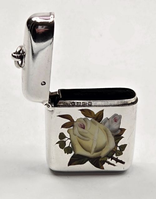 fig 3. A rectangular sterling silver vesta case featuring hand-painted yellow and white roses in enamel with a top suspension loop.