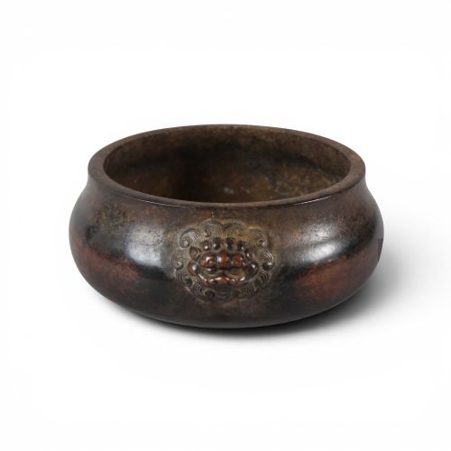 fig 1. A heavy dark brown cast bronze incense burner featuring a low compressed circular form decorated with relief beast mask handles.