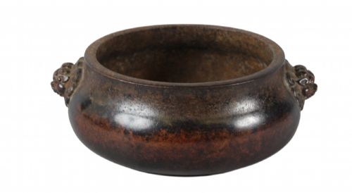 fig 3. A heavy dark brown cast bronze incense burner featuring a low compressed circular form decorated with relief beast mask handles.