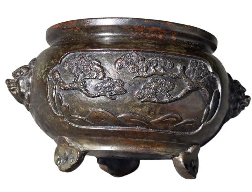 fig 6. A dark patinated cast bronze incense burner featuring raised relief panels of bamboo and beast mask side handles.