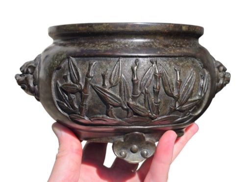 fig 7. A dark patinated cast bronze incense burner featuring raised relief panels of bamboo and beast mask side handles.