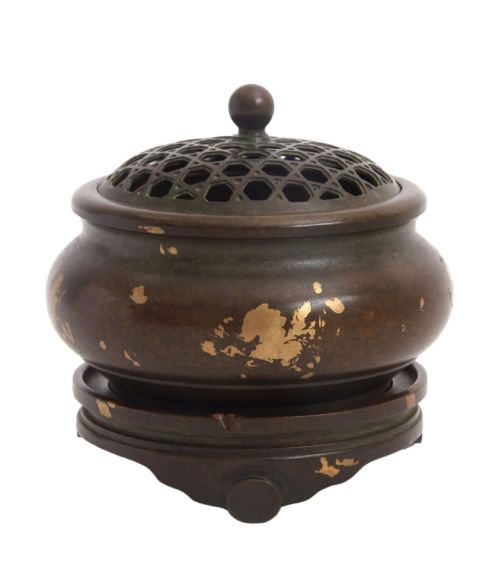 fig 4. A dark brown bronze circular censer featuring gold splash decoration, a reticulated lattice cover with a spherical finial, and a matching footed bronze stand.