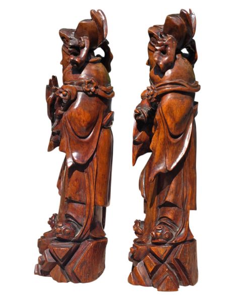 fig 3. A pair of Chinese hardwood sculptures depicting Daoist immortals in flowing robes with carved geometric bases.