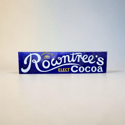 fig 3. A rectangular cobalt blue vitreous enamel advertising sign featuring white script reading Rowntrees Cocoa and yellow lettering reading Elect Cocoa, topped with a royal warrant crest.
