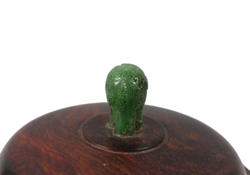 fig 4. A rounded dark bronze Chinese censer with elephant head handles, topped with a polished wood lid featuring a green jade finial, resting on a carved hardwood stand.