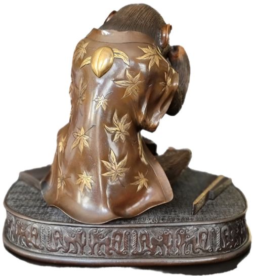 fig 2. A dark bronze Japanese okimono sculpture depicting an anthropomorphic monkey wearing spectacles, seated with a book and inro.
