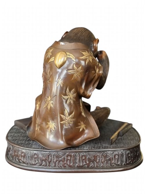 fig 7. A dark bronze Japanese okimono sculpture depicting an anthropomorphic monkey wearing spectacles, seated with a book and inro.