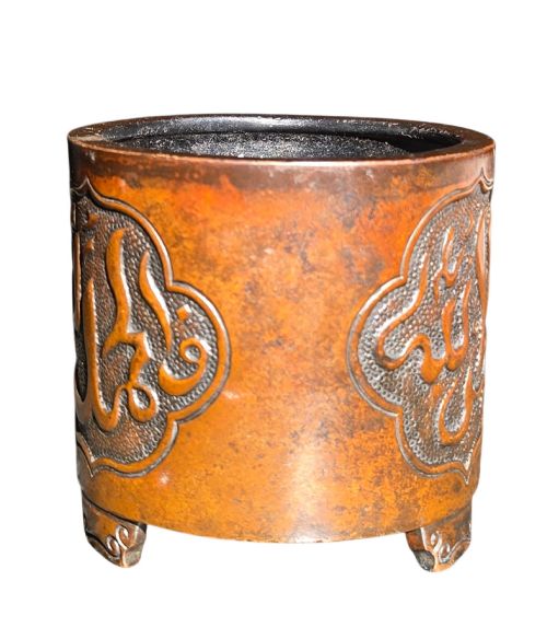 fig 2. A cylindrical warm brown bronze tripod censer featuring a raised lobed cartouche with Arabic calligraphy set against a textured ground.