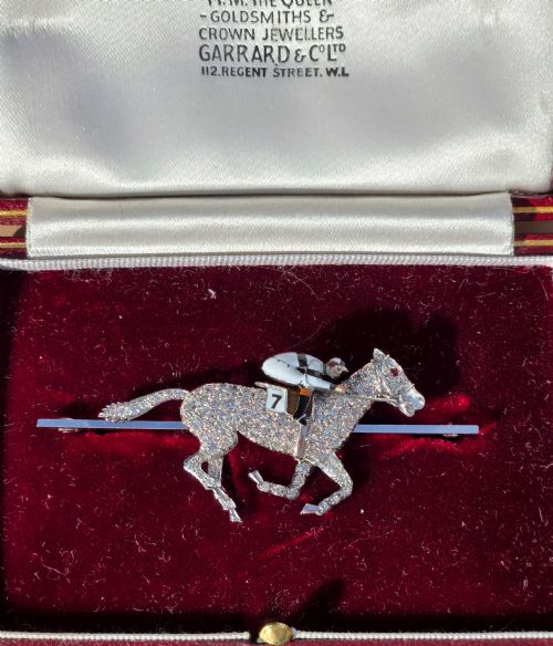 fig 3. A platinum-topped 18ct gold brooch shaped as a galloping racehorse set with diamonds, ridden by a jockey in black and white enamel silks with number seven.