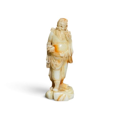 fig 1. A carved pale celadon and russet nephrite jade standing figure of an immortal holding a vessel on a carved rockwork base.