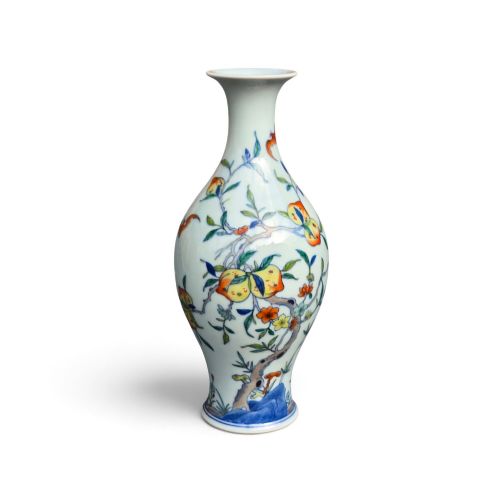 fig 1. A Chinese porcelain garlic-head vase decorated with hand-painted peaches, orange bats, green leaves, and blue rockwork on a white background.