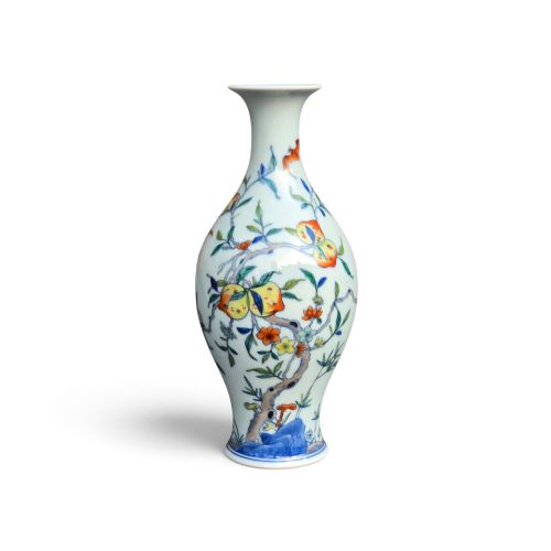 fig 2. A Chinese porcelain garlic-head vase decorated with hand-painted peaches, orange bats, green leaves, and blue rockwork on a white background.