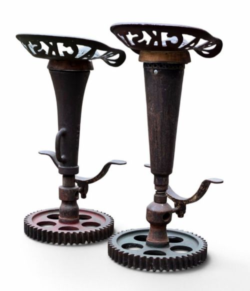 fig 1. A pair of heavy industrial bar stools constructed with embossed Blackstone and Company cast-iron tractor seats, central metal columns with integrated footrests, and heavy gear cog bases.