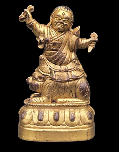 fig 1. A sixteenth to seventeenth-century Sino-Tibetan gilt-bronze votive figure depicting a wrathful deity seated on a tiger atop a lotus pedestal.
