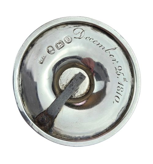 fig 2. A small George III sterling silver taperstick featuring a flared sconce, a square central collar, a side ring handle, and a moulded circular base.
